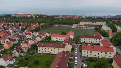 Aerial-view-going-towards-two-football-fields-called-Harlandaplan,-with-the-Harlanda-Orgryte-library-in-the-background-and-suburban-family-houses-and-apartements-around-them-in-Gothenburg