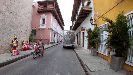 An-Afro-American-woman-is-carrying-her-bike-through-a-street-in-the-old-town-of-Cartagena-de-Indias,-Colombia