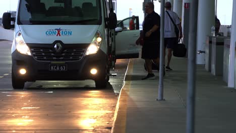 Passenger-movement-charge-travel-tax-concept-shot,-hassle-free-and-convenient-ConXion-shuttle-transfer-stopped-at-international-departure-terminal,-dropping-off-travellers-at-Brisbane-airport