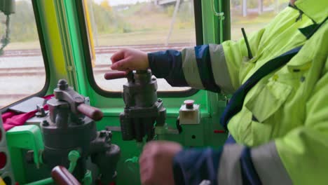 El-Conductor-Tira-De-Palancas-Y-Opera-El-Tren-Dentro-De-Una-Cabina,-En-Medio-Plano,-Cámara-En-Mano.