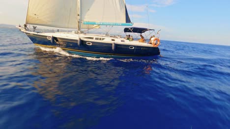 FPV-aerial-circling-a-sailing-yacht-coasting-along-the-ocean-on-a-clear,-sunny-day