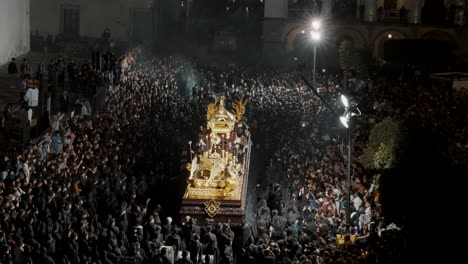 Personas-Vestidas-De-Negro-Llevando-Una-Carroza-Gigante-Durante-La-Procesión-De-Semana-Santa-En-Antigua,-Guatemala---Drone-Estático