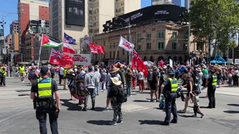 Police-keeping-an-eye-on-protesters-in-Melbourne-Australia-walking-down-Collins-Street-stopping-all-traffic,-protesting-against-Dan-Andrews