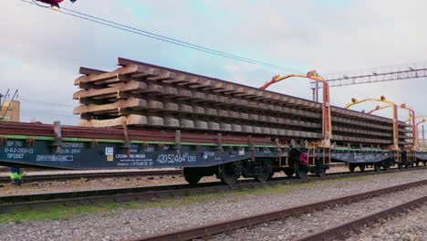 stack-of-new-train-tracks-move-along-train-wagon,-wide-shot,-camera-pan