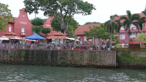 Dining-tables-lines-at-Malacca-river-with-passing-tourist-boats-Malaysia