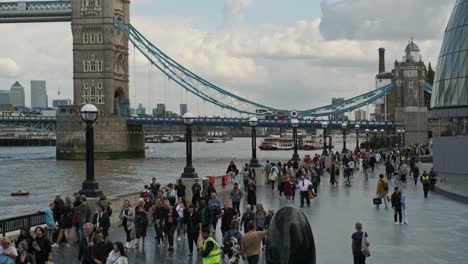 Eine-Menschenmenge-Geht-An-Der-Tower-Bridge-Und-Dem-Kuppelgebäude-In-London,-Vereinigtes-Königreich,-Vorbei