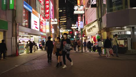Tokyo-Shibuya-Shopping-Streets,-Tilt-Down-Reveal-of-Busy-Japan-at-night