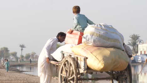 Padre-Revisando-Carro-De-Madera-Con-Sacos-E-Hijo-En-Caminos-Rurales-En-Sindh.