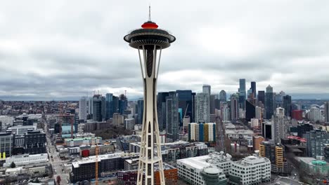 Seattle-space-needle-aerial-view-panning-across-cloudy-overcast-downtown-district-skyscraper-skyline