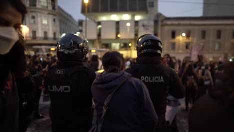 A-woman-jumps-and-sings-right-next-to-policemen-who-are-standing-in-front-of-a-group-of-women-who-march-during-a-protest-in-the-International-Women's-day-in-Quito,-Ecuador