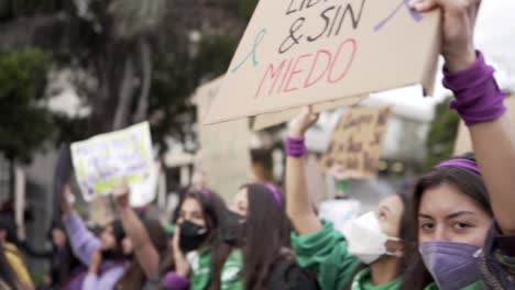 Women-wearing-masks-are-holding-up-signs-with-phrases-of-protest-during-the-International-Women's-day-in-Quito,-Ecuador