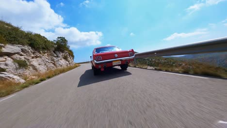 Cinematic-FPV-aerial-following-a-classic-red-Mustang-along-a-picturesque-country-road