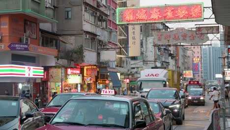 Neon-signs-hang-above-a-road-and-traffic-in-a-residential-neighborhood