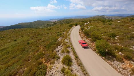 Cinematic-FPV-aerial-following-a-vintage-red-Mustang-through-a-scenic-mountain-landscape