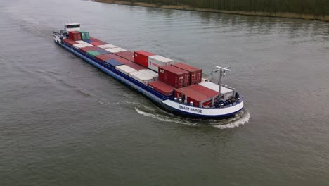 Small-container-ship-navigating-through-the-inland-canal,-aerial-video