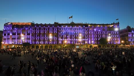 Aerial-view-over-people-protesting-in-front-a-illuminated-building-in-Mexico-city---reverse,-drone-shot