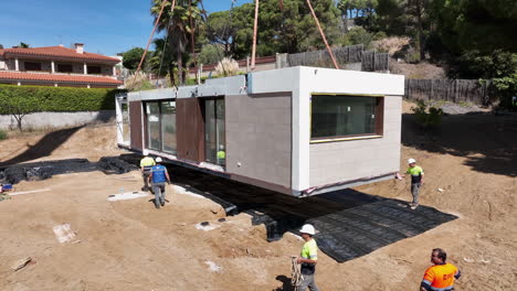 Trabajadores-De-La-Construcción-Revisando-El-Módulo-De-Casa-Prefabricada-Antes-De-Colocarlo