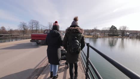 Women-Walking-Across-The-Bridge-With-Baby-Stroller-In-Motala,-Sweden