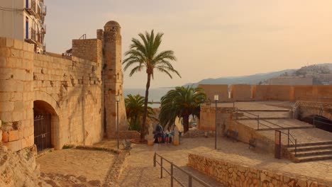 Tourists-Entering-The-Exit-Way-Of-Peniscola-Castle-At-Sunset-Time-In-Castellon,-Spain