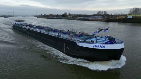 Drone-follow-shot-of-the-fuel-barge-Luana-sailing-on-full-speed-on-a-dutch-river