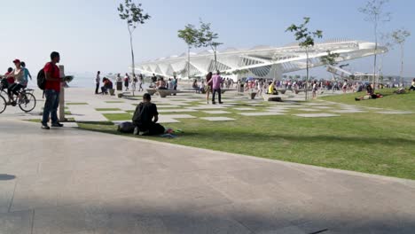 People-chilling-and-looking-at-Baia-de-Guanabara-and-Museu-do-Amanha,-tomorrows-museum,-at-Praca-Maua,-at-sunset,-in-the-center-of-Rio-de-Janeiro,-Brazil,-on-a-Sunday-afternoon