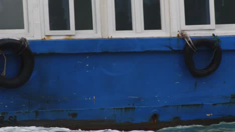 Close-up-shot-of-the-blue-ferry-boat-sailing-on-the-waters-of-Ha-Long-Bay,-Vietnam