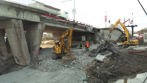 Excavators-working-on-pile-of-rubble-below-highway-bridge-repair-site
