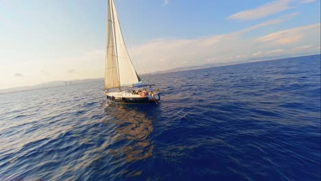FPV-aerial-flying-toward-a-sailing-yacht-coasting-along-the-bright,-blue-water-of-the-Mediterranean-Sea