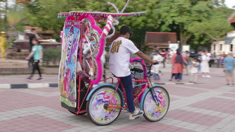 El-Jinete-Sale-En-Un-Triciclo-Rosa-Decorado-Con-Lindos-Ponis,-Toma-De-Seguimiento