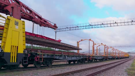 railway-railroad-construction-train-unloading-new-train-track,-wide-shot,-static