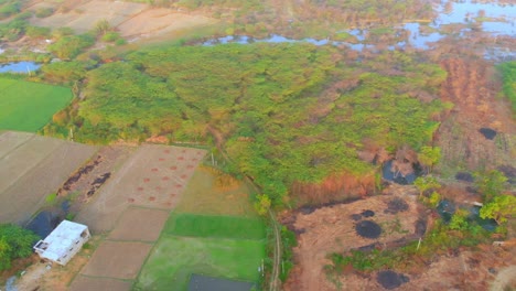 A-drone-shot-of-a-village-located-by-a-small-river-and-farm-lands