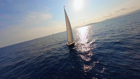 FPV-aerial-flying-around-a-yacht-sailing-on-the-bright,-blue-water-of-the-Mediterranean