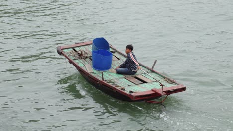Vietnamese-Man-Sitting-On-His-Boat-Cruising-In-The-Ha-Long-Bay-In-Vietnam