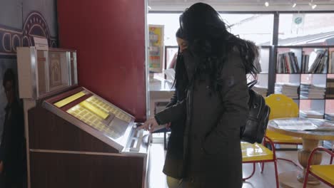 Zwei-Frauen-Drücken-Auf-Die-Knöpfe-Einer-Alten-Jukebox-Maschine-Im-Motala-Motormuseum-In-Schweden