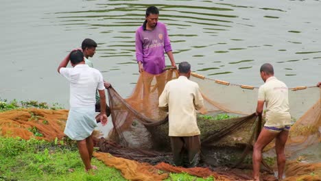 close-up-shot-of-a-group-of-Fishermen-gathering-and-setting-their-fishing-nets-up-on-the-grass-with-the-river-in-the-background