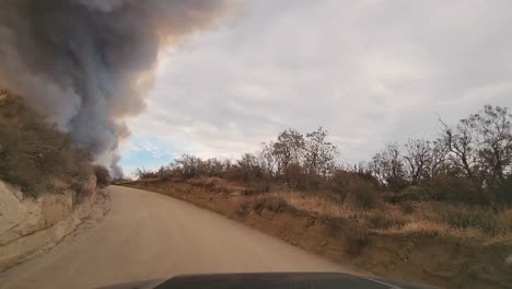 A-front-view-of-a-car-driving-toward-a-wildfire-in-the-desert