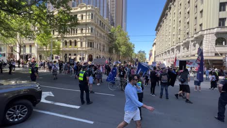 Protesters-rally-in-Melbourne-Australia-walking-down-Collins-Street-stopping-all-traffic,-police-escorting-the-protesters