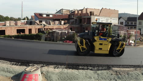 Worker-operating-steamroller-machine-to-flatten-new-asphalt-city-road