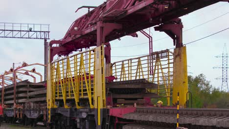 Railway-railroad-construction-crane-unloading-rail-track,-wide-shot,-camera-pan-right