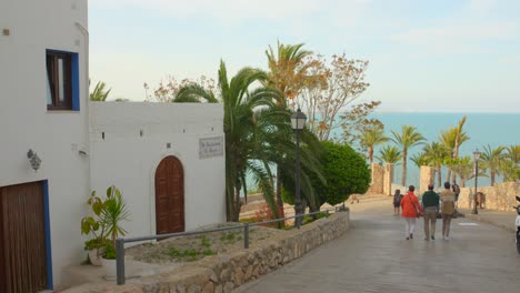 Stunning-View-Of-Tourists-Walking-On-Pathway-Going-Nearby-Peniscola-Sea-In-Castellon,-Spain