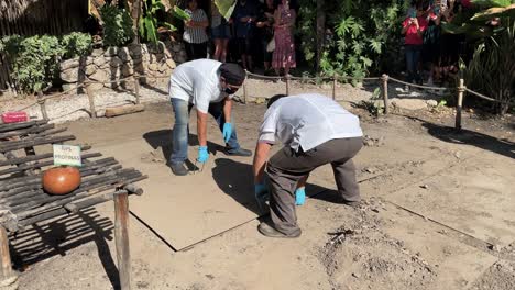 slow-motion-shot-of-chefs-removing-cochinita-pibil-from-the-ground-oven