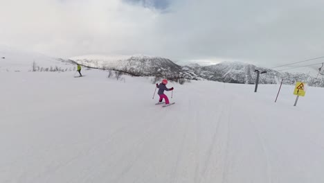 Niña-Vestida-De-Rosa-Y-Púrpura-Esquiando-Cuesta-Abajo-Como-Una-Profesional---Cámara-Siguiendo-A-Un-Niño-Pequeño-Esquiador-Desde-Atrás-En-Myrkdalen,-Noruega