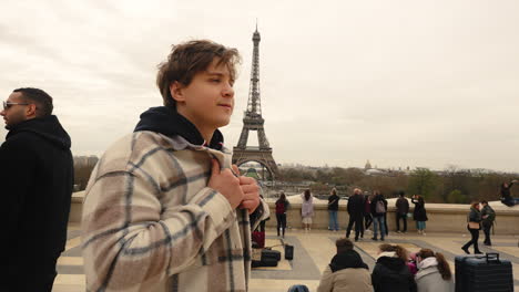 Junger-Kaukasischer-Europäischer-Mann-Passt-Seine-Jacke-In-Zeitlupe-An,-Mit-Dem-Eiffelturm-Hinter-Ihm