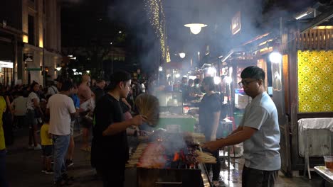 Szene-Mit-Satay-Verkäufern,-Die-Die-Flammen-Des-Satay-Anfachen,-Und-Touristen-Und-Einheimische-In-Lau-Pa-Sat-Singapur-Schlange-Stehen,-Um-Essen-Zu-Kaufen