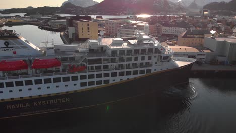 Close-aerial-drone-shot-of-a-big-cruise-ship-docking-in-a-harbour-in-Lofoten,-Norway