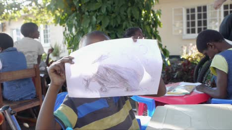 Mittlere-Ansicht-Eines-Jungen-Afrikanischen-Kindes,-Das-Eine-Wunderschöne-Buntstiftzeichnung-Eines-Elefantentieres-Zeigt