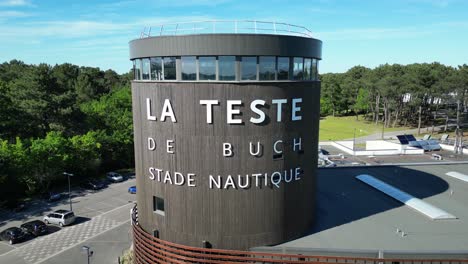 Olympic-sized-swimming-pool-stadium-with-freediving-tower-near-entrance,-Aerial-dolly-out-shot