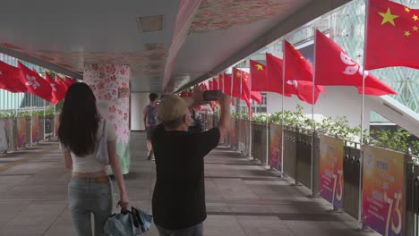 Ein-Mann-Fotografiert-Die-Im-Wind-Wehenden-Chinesischen-Und-Hongkong-Flaggen-Während-Des-Chinesischen-Nationalfeiertags,-Dem-Gründungstag-Der-Volksrepublik-China