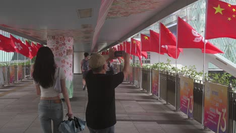 Un-Hombre-Toma-Fotografías-De-Banderas-Chinas-Y-De-Hong-Kong-Ondeando-Al-Viento-Durante-El-Día-Nacional-De-China,-El-Aniversario-De-La-Fundación-De-La-República-Popular-China.