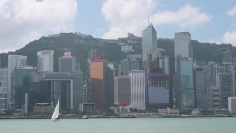 A-sailboat-navigates-through-Victoria-harbor-in-front-of-the-Hong-Kong-skyline